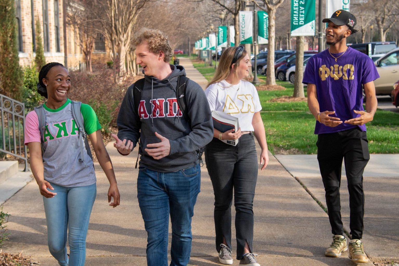 Greek Life students walking and engaging with each other on campus.